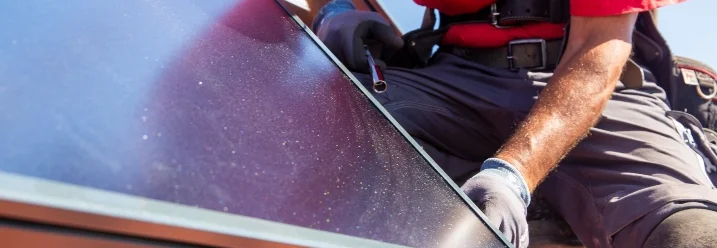 Person montiert Solarpanel auf Dach